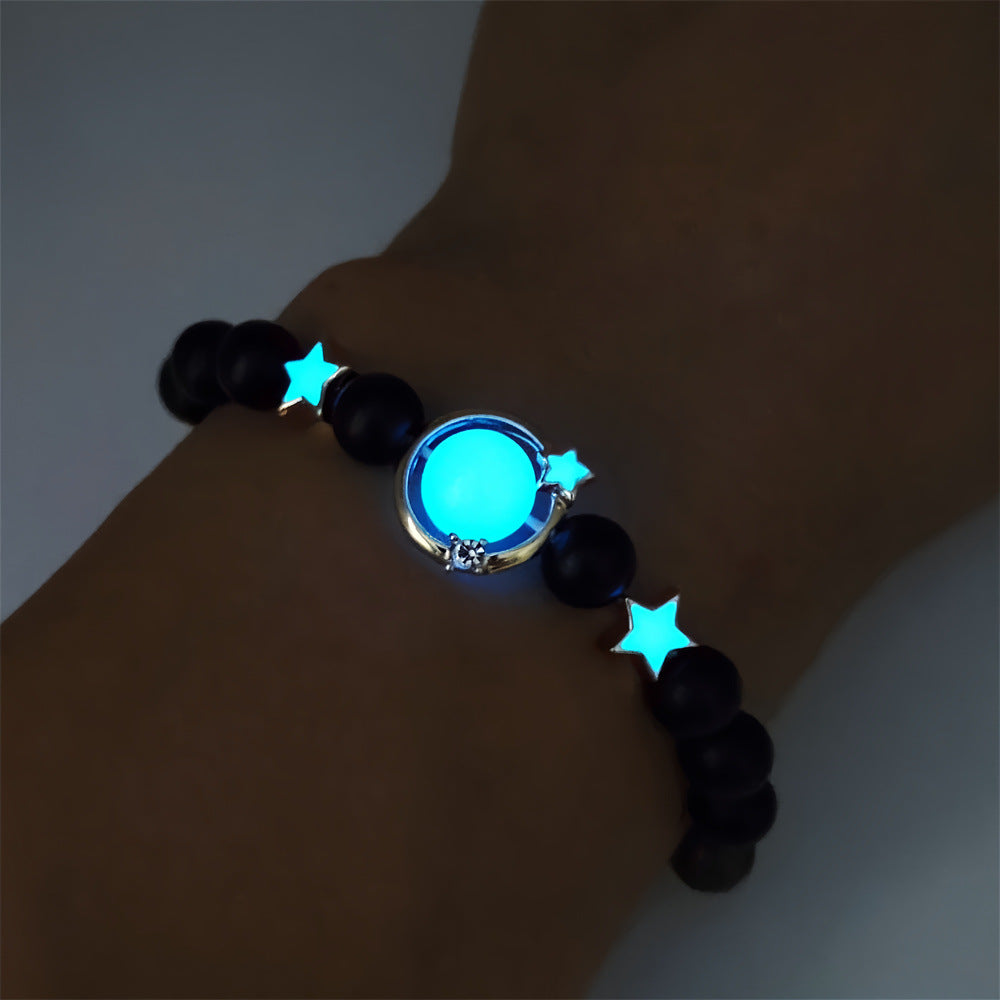 Glowing bracelet with black beads and blue star-shaped lights on a wrist against a dark background