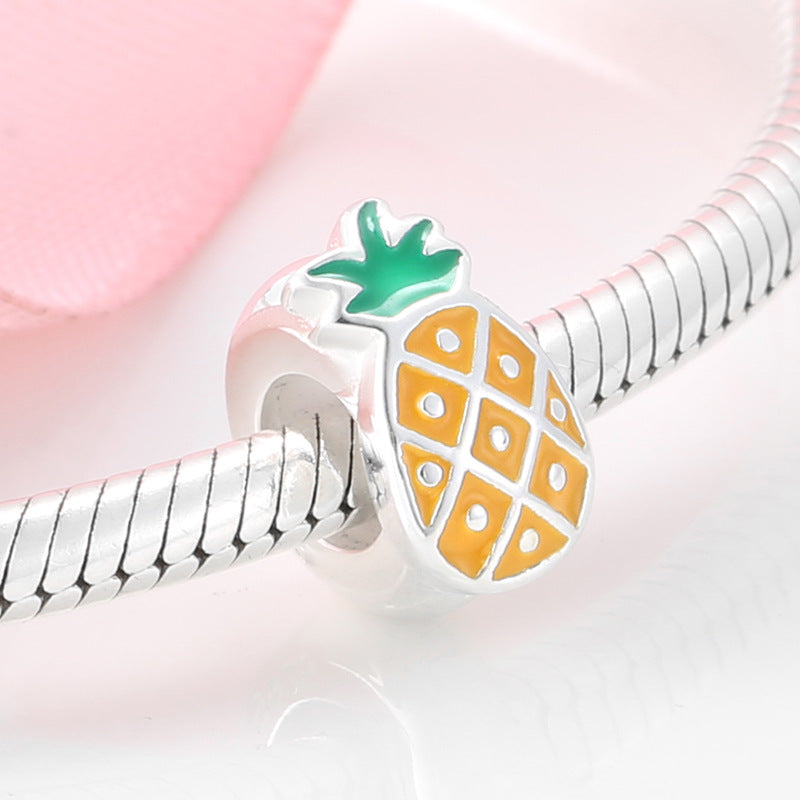 Silver charm with a pineapple design on a pink background