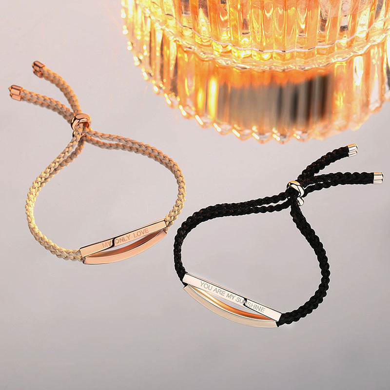 Two bracelets, one gold and one black, with engraved text on a neutral background.