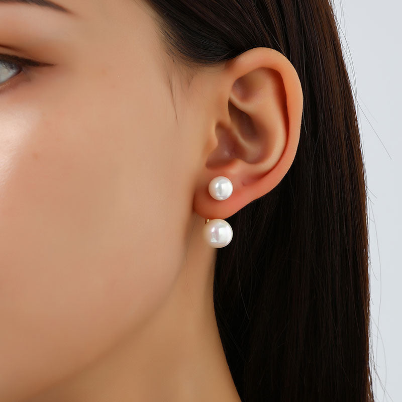 Close-up of a woman's ear wearing pearl earrings with a neutral background