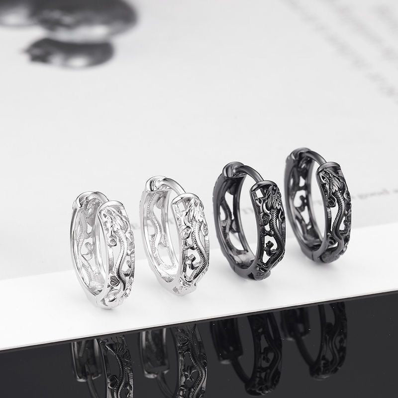 Four silver rings with intricate designs on a reflective surface.