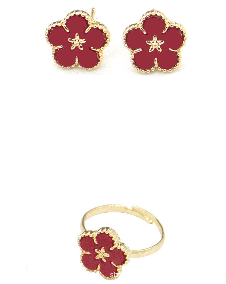 Red flower-shaped earrings with gold accents on a white background