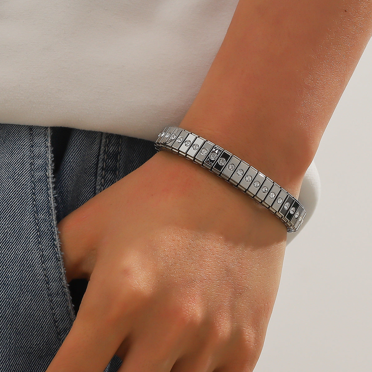 Silver bracelet on a wrist with a neutral background