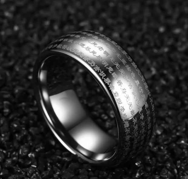 Silver ring with engraved text on a textured black background