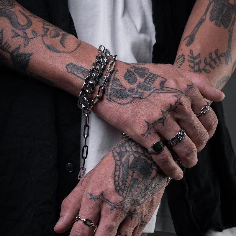 Close-up of tattooed hands with jewelry on a dark background
