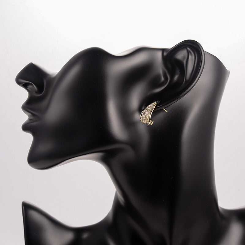 Gold earring on a black mannequin ear display against a white background