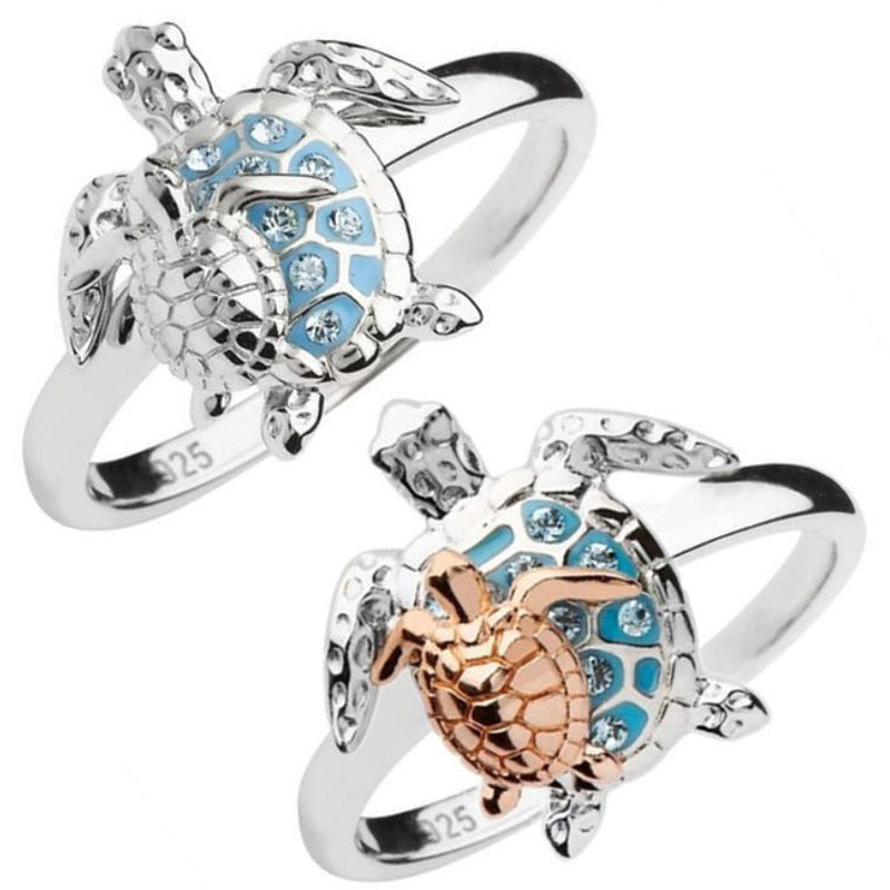 Two turtle-shaped rings with blue gemstones on a white background