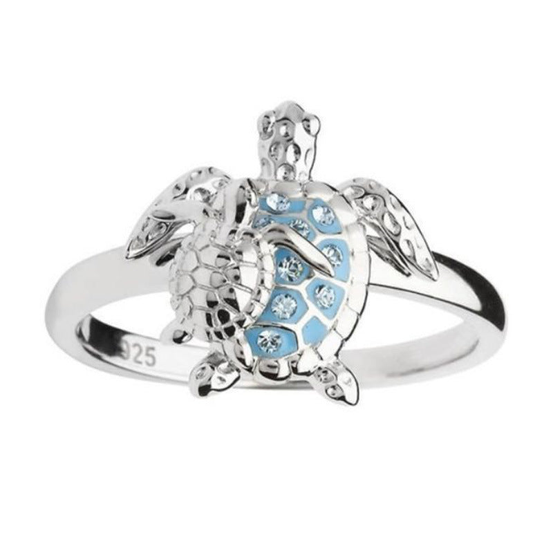 Silver turtle-shaped ring with blue accents on a white background