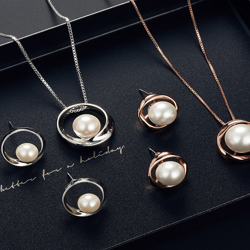 Pearl jewelry set including necklaces and earrings on a dark surface.