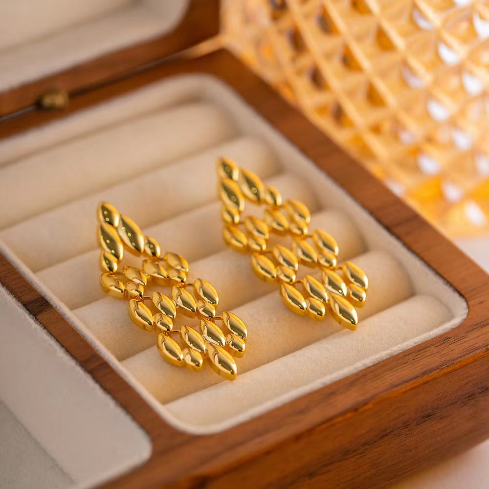 Gold earrings in a wooden jewelry box with a warm glow.