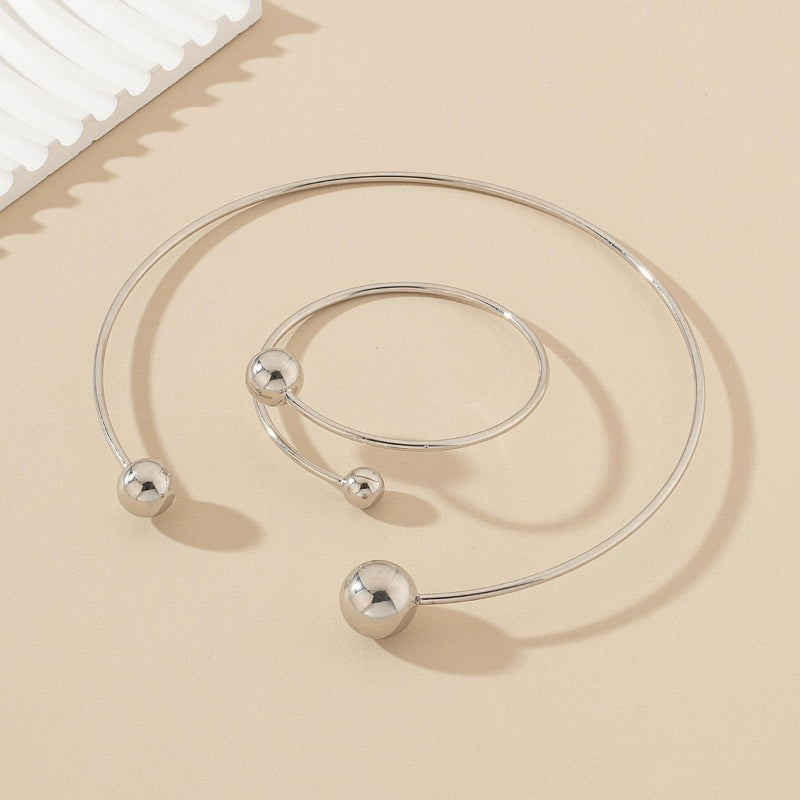 Silver bracelet with spherical ends on a beige surface