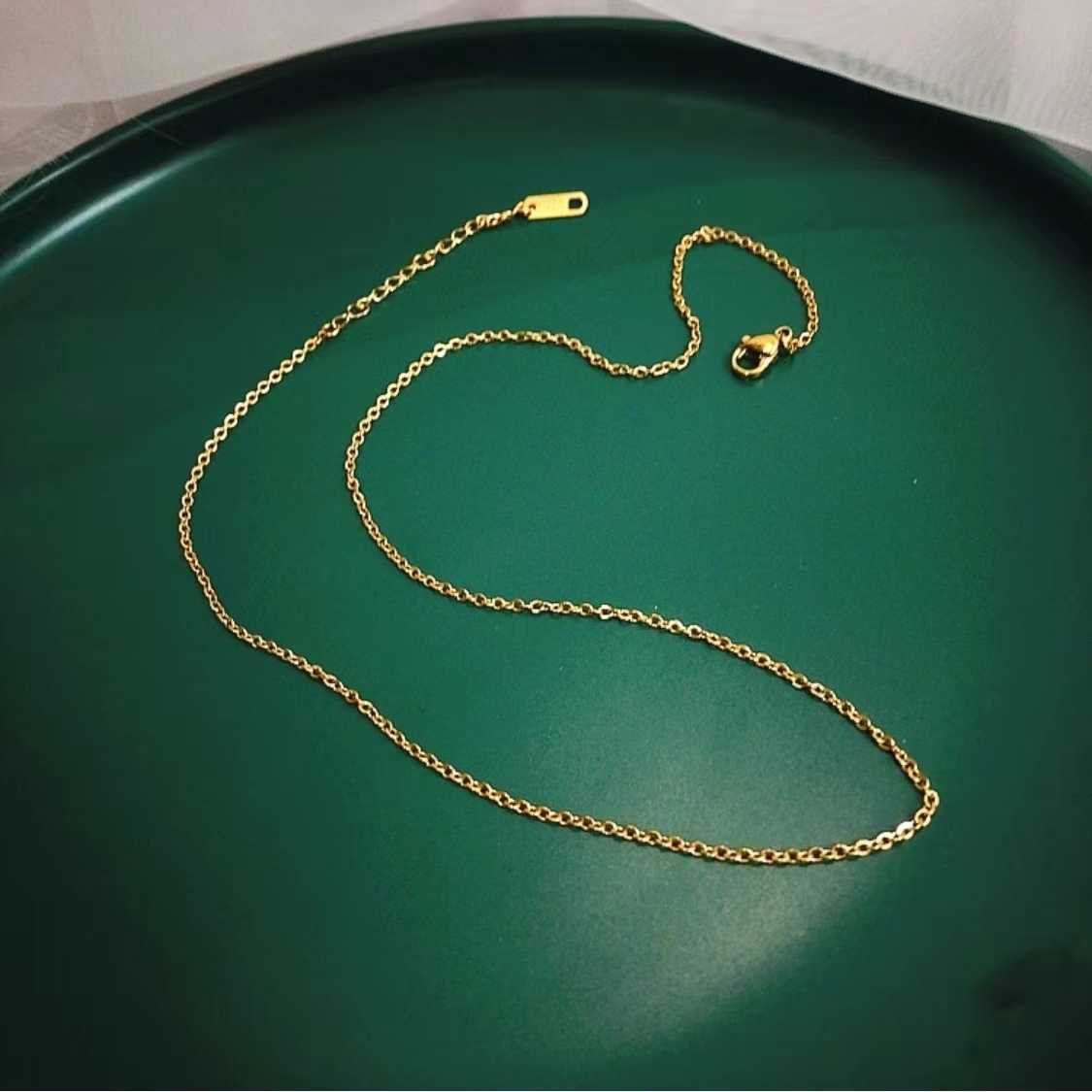Gold chain necklace on a green tray
