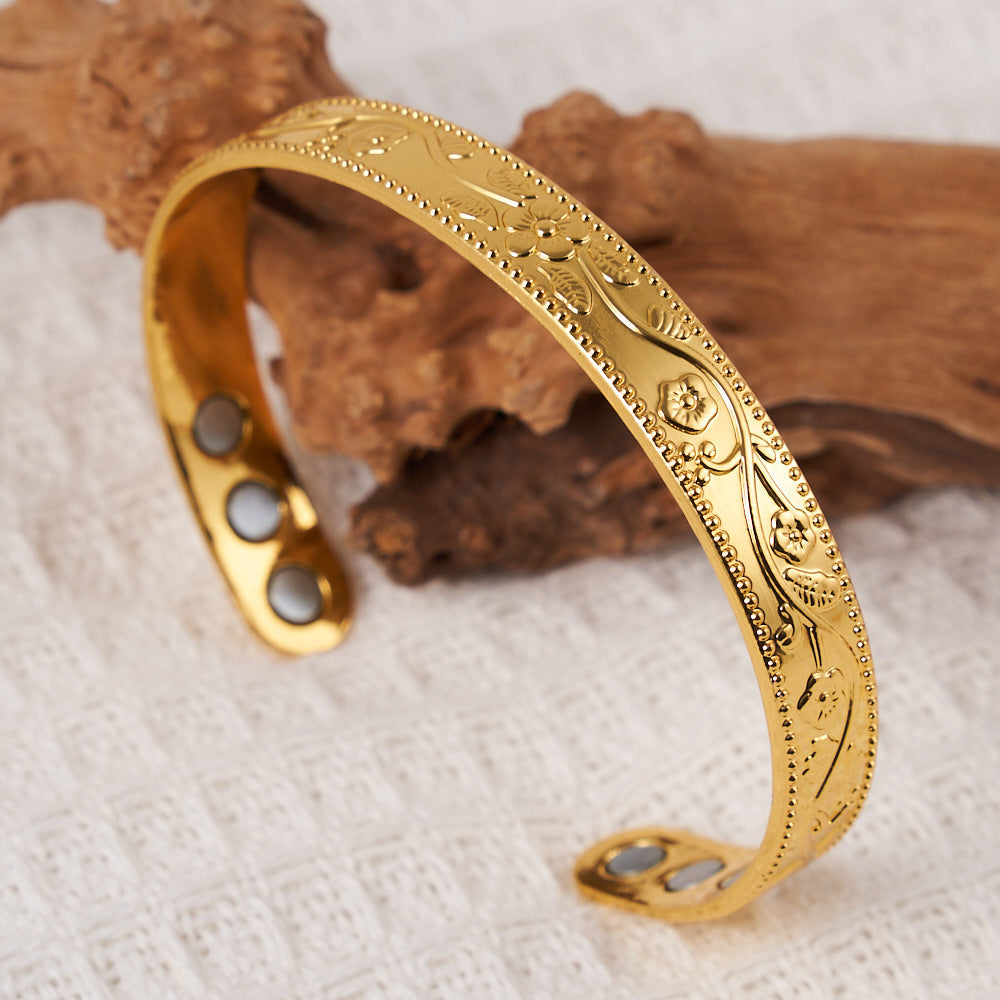 Gold bracelet with intricate designs on a textured surface