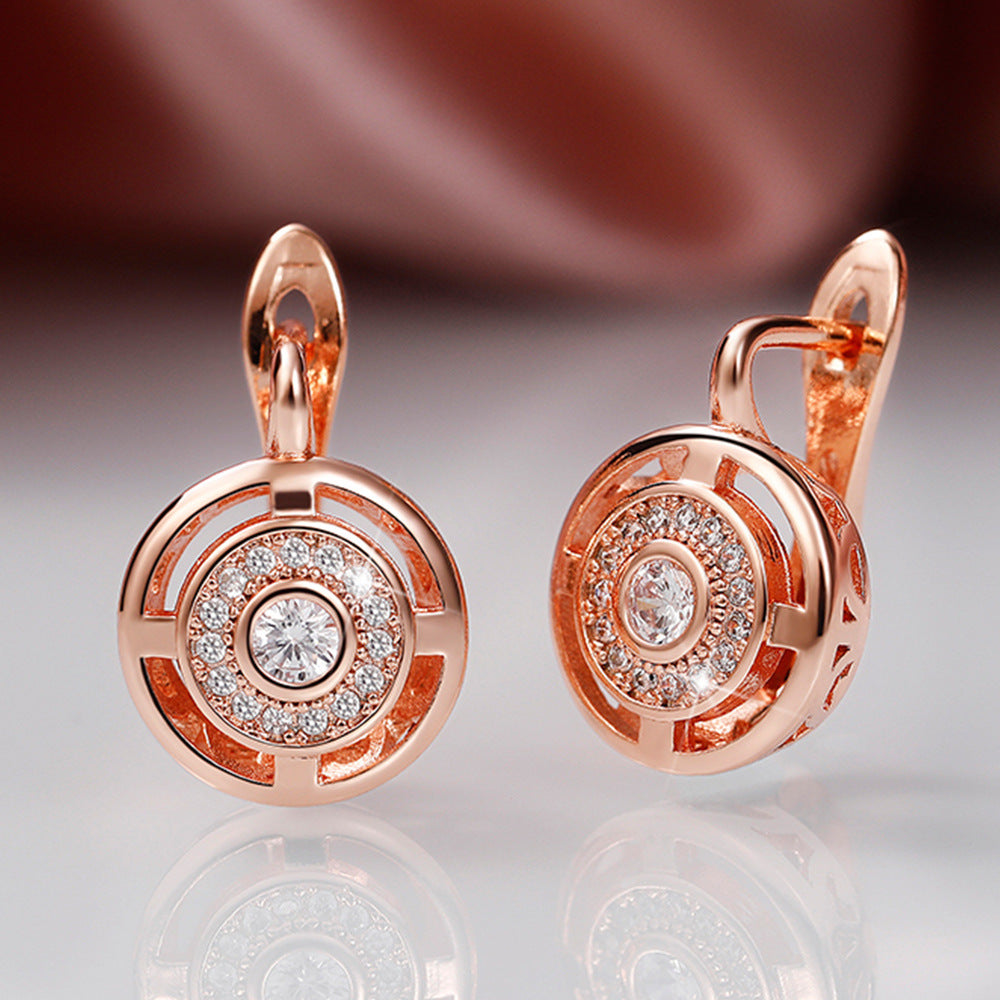 Rose gold earrings with diamond accents on a reflective surface