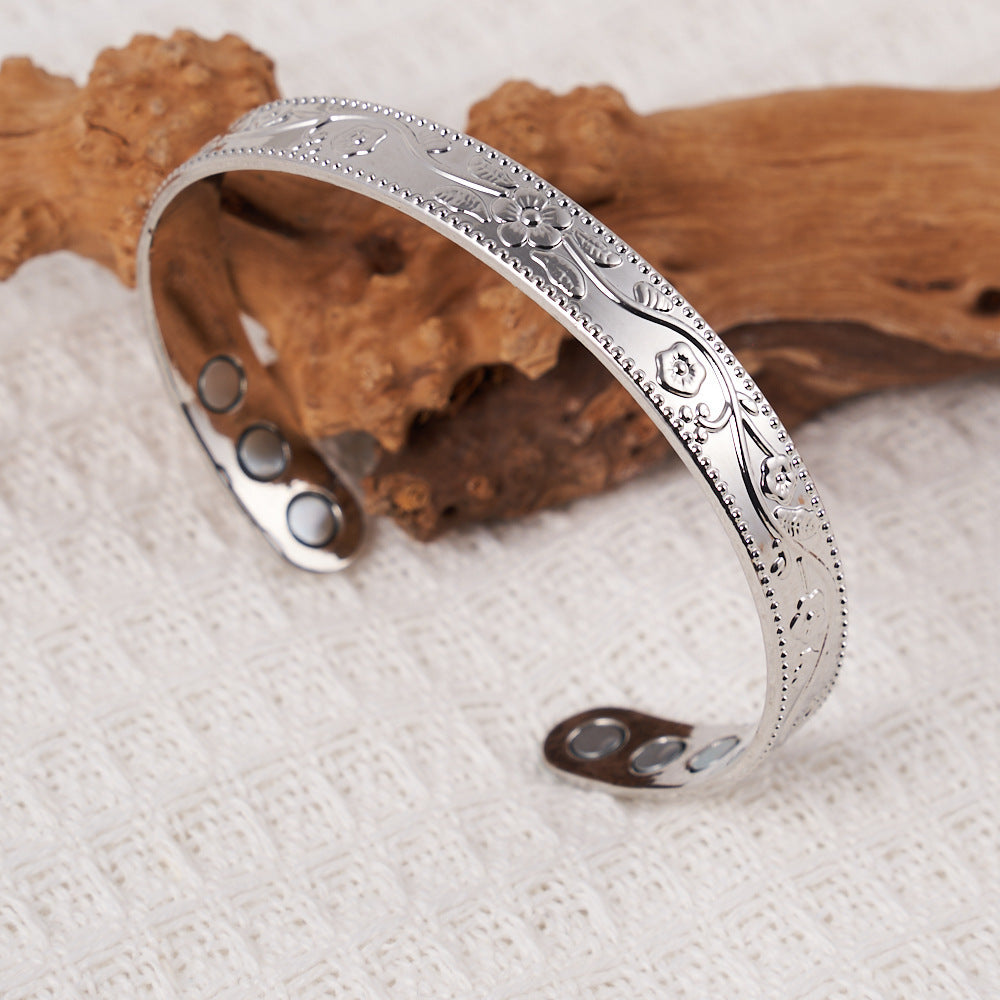 Silver bracelet with intricate designs on a white fabric background