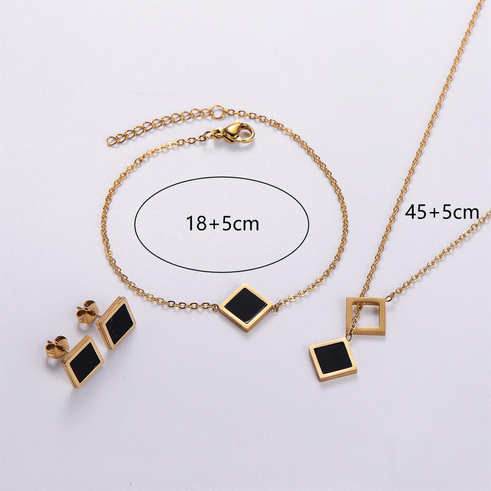 Gold jewelry set with black square pendants on a light gray background