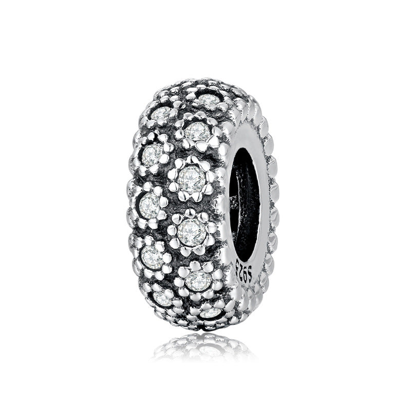 Silver charm with embedded stones on a white background