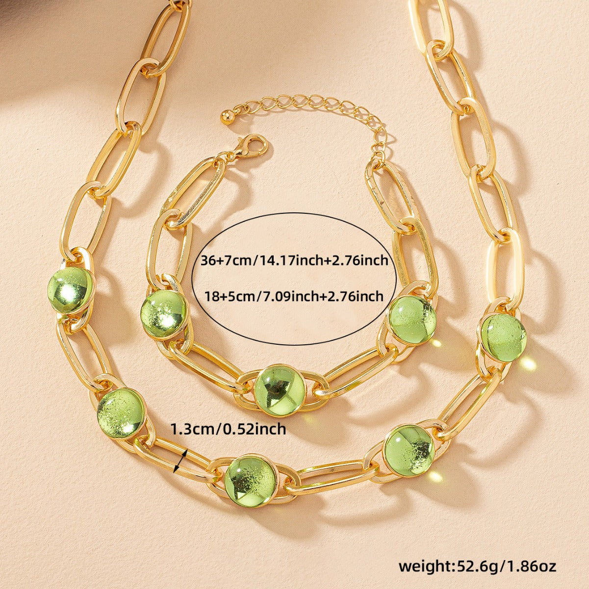 Gold chain necklace with green gemstones on a beige background
