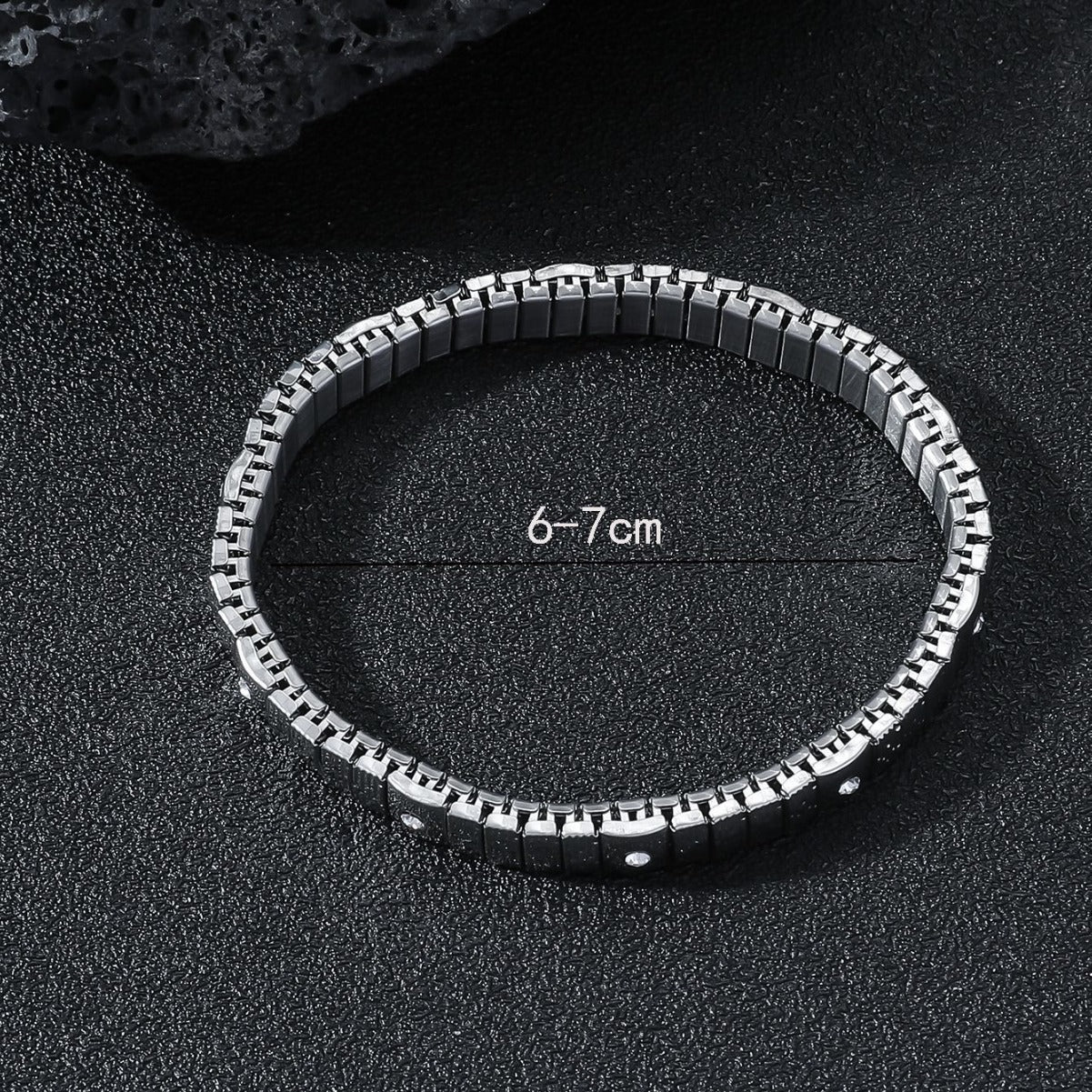 Silver bracelet on a black textured surface with measurement text.