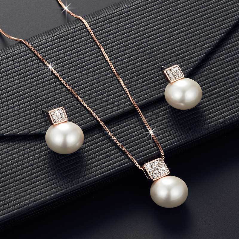 Pearl necklace and earrings set on a dark fabric background