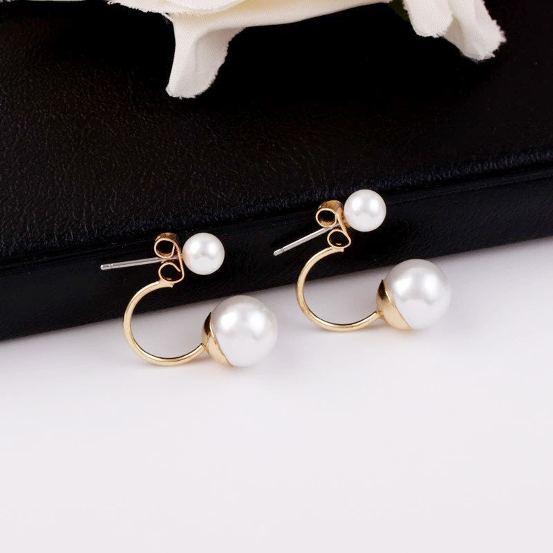 Pearl earrings with gold hooks on a white surface with a black background