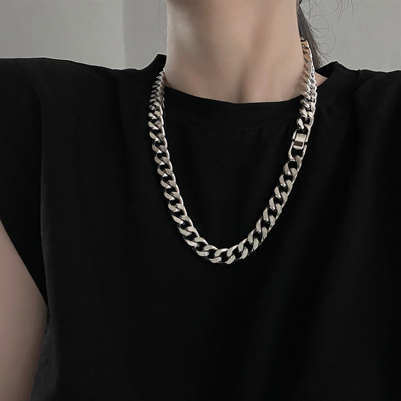Person wearing a thick chain necklace on a plain background