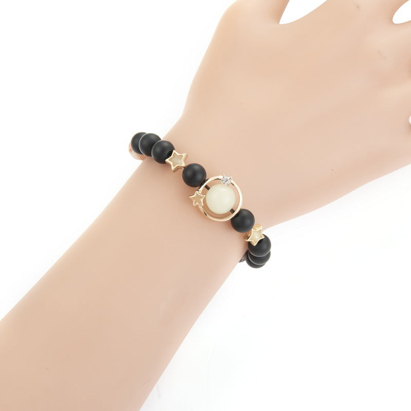 Black beaded bracelet with gold accents on a wrist against a white background