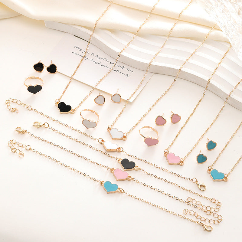 Collection of gold necklaces with heart-shaped charms on a white surface.