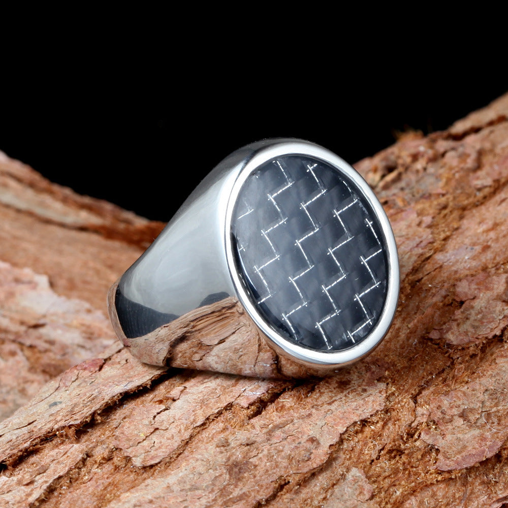 Silver ring with a textured black stone on a wooden surface