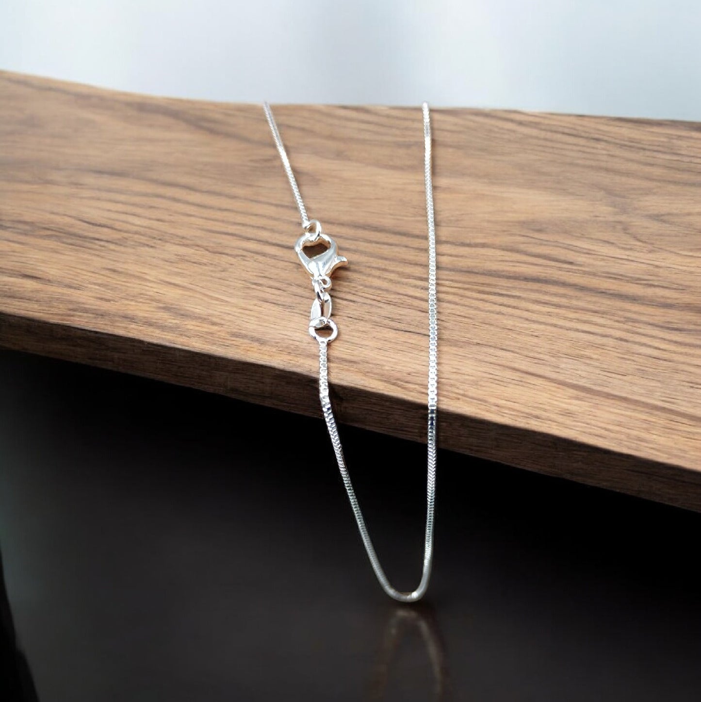 Silver chain necklace on a wooden surface