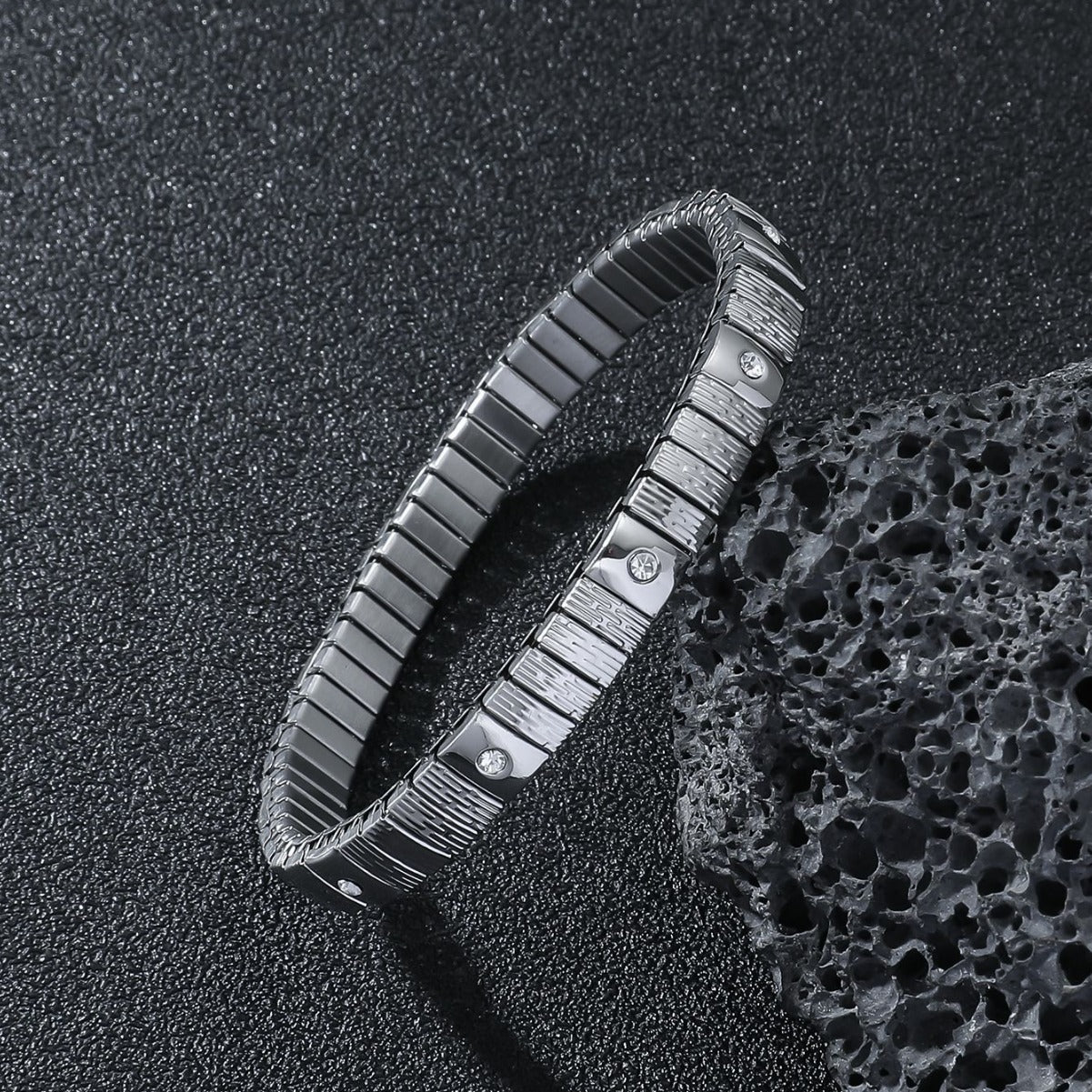Metallic bracelet with textured design on a textured black surface
