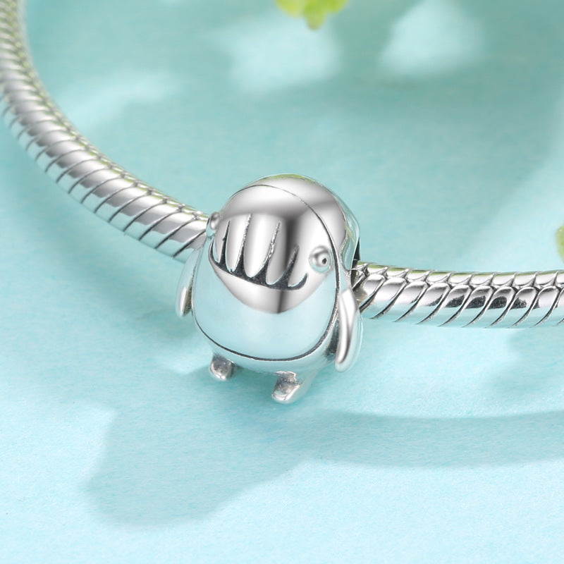 Silver charm shaped like a dog on a light blue background