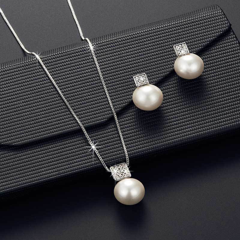Pearl necklace and earrings set on a black textured surface