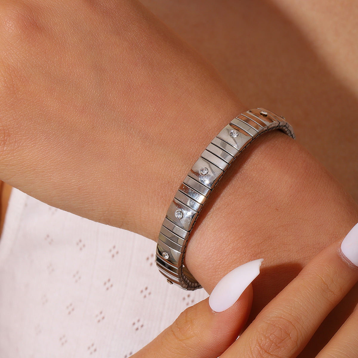 Silver bracelet with diamond accents on a wrist against a neutral background