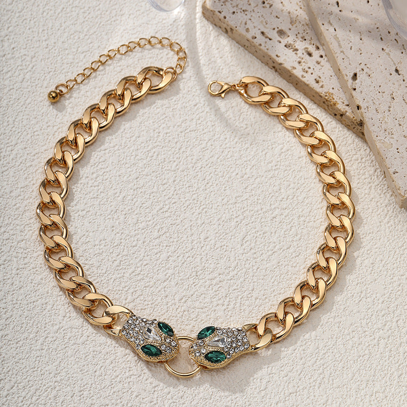 Gold chain necklace with green gemstones on a light background