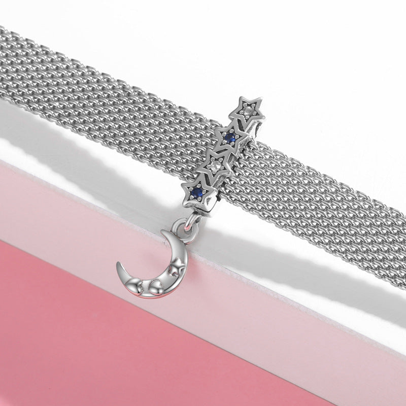 Silver chain necklace with star and moon pendants on a pink and white background