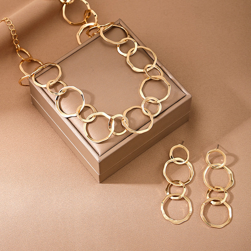Gold chain necklace and earrings on a brown surface