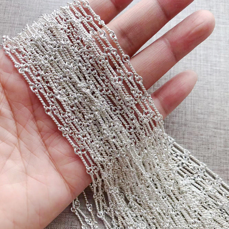 Silver chain held in a hand against a neutral background