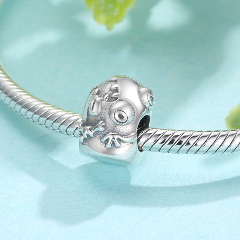 Silver charm with a skull design on a light blue background