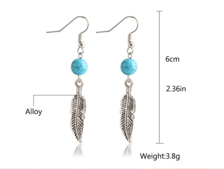 Silver-toned dangle earrings with turquoise blue beads and feather charms, shown on a white background with measurement labels indicating 6 cm length, 2.36 inch drop, and 3.