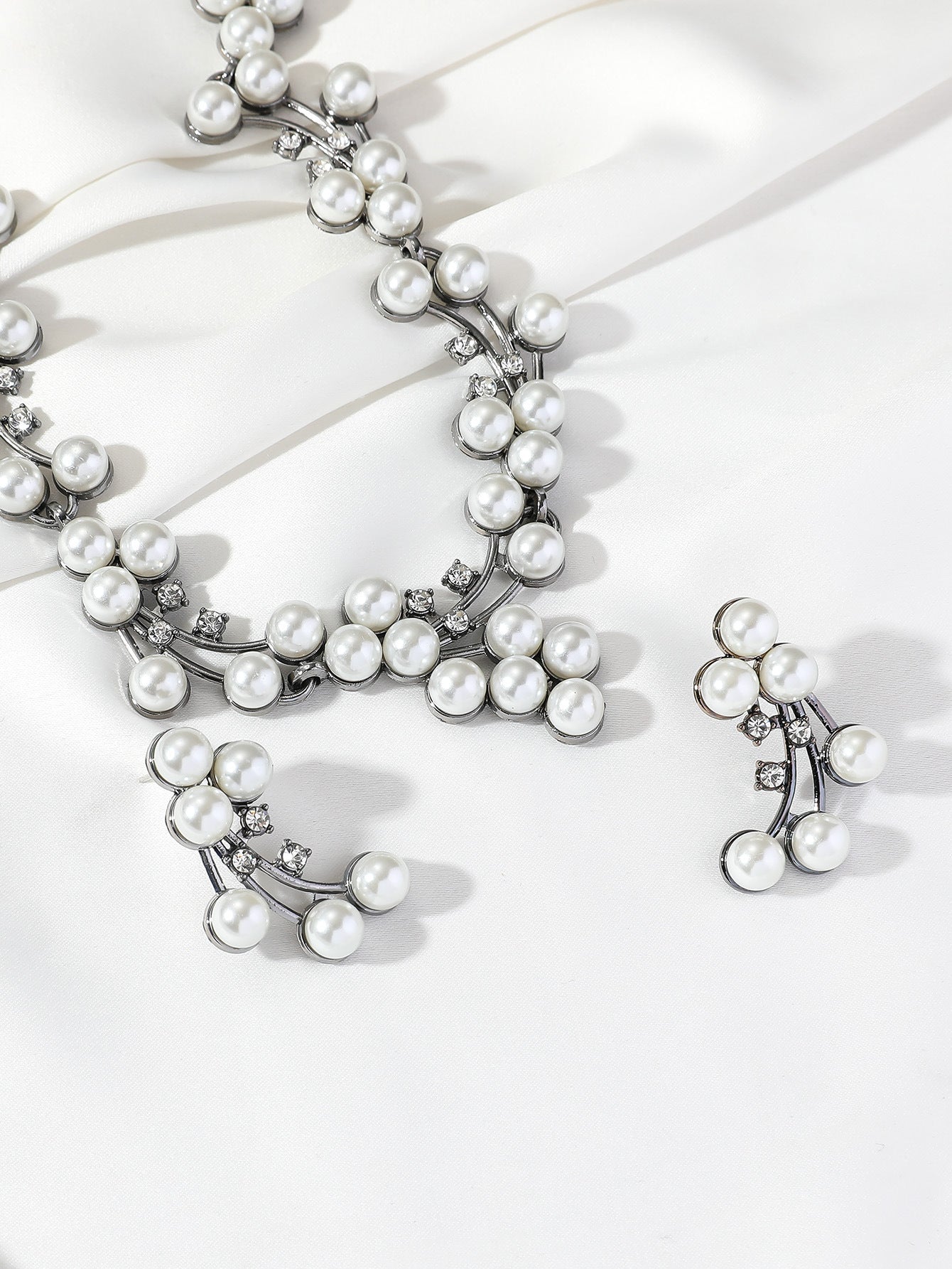 Pearl necklace and earrings on a white background