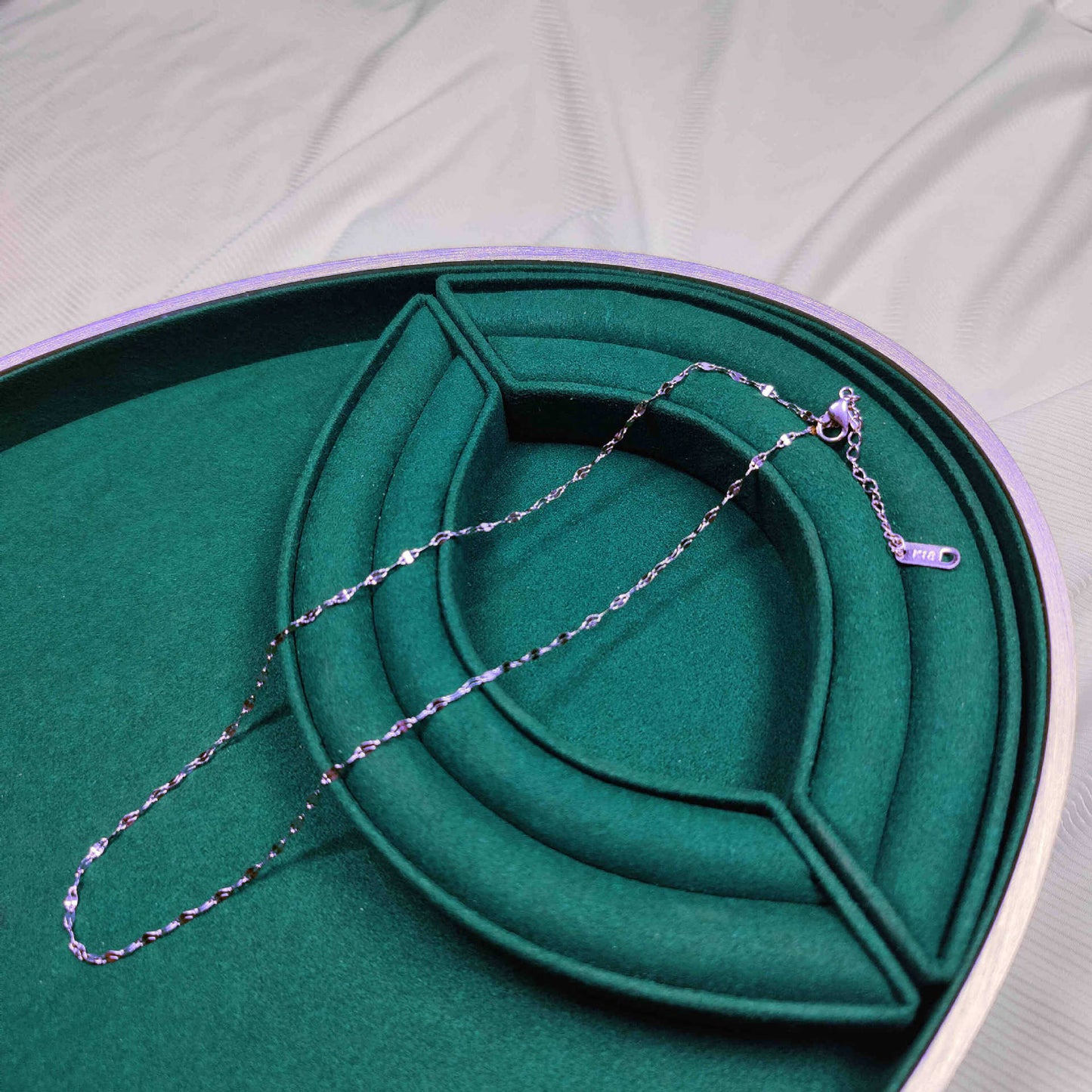 Silver necklace on a green jewelry box
