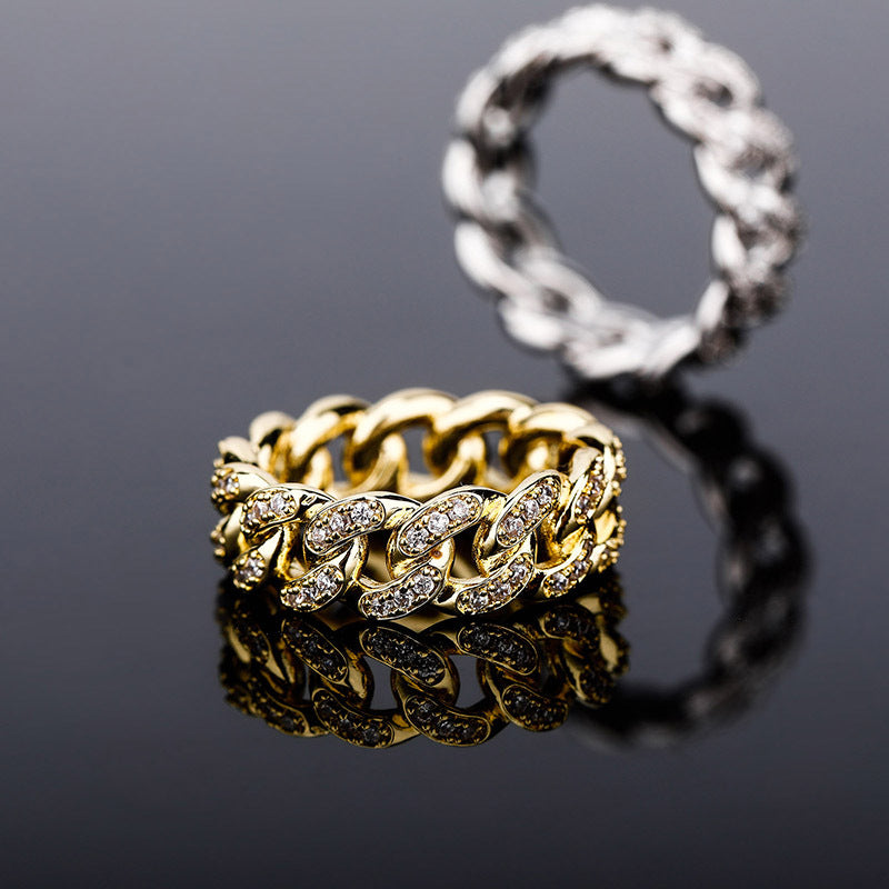 Gold and silver chain-link rings on a reflective black surface