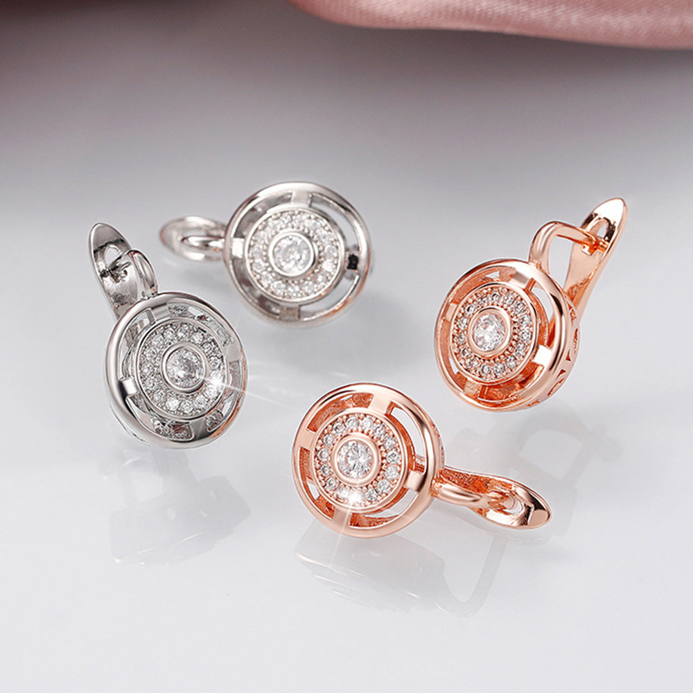 Pair of silver and rose gold earrings with diamond-like centers on a light gray background