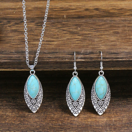 Turquoise stone jewelry set with silver chain necklace and earrings on a wooden background