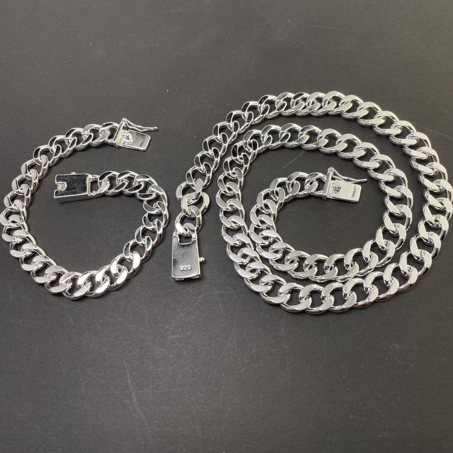 Silver chain necklace and bracelet on a dark surface