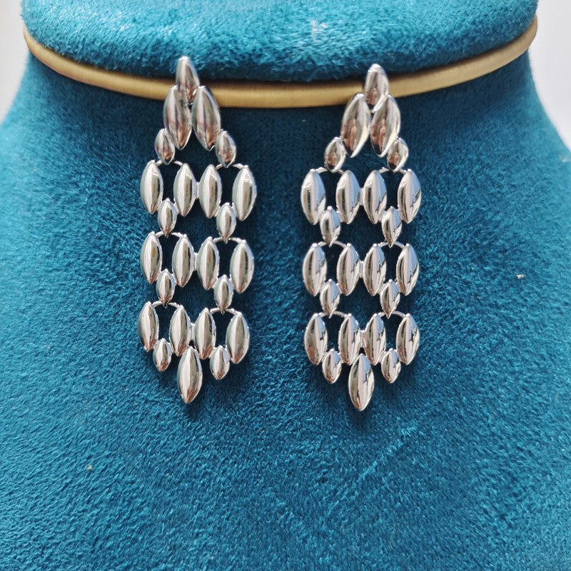 Silver chandelier earrings on a blue velvet stand