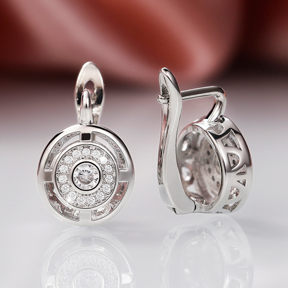 Silver earrings with diamond accents on a reflective surface