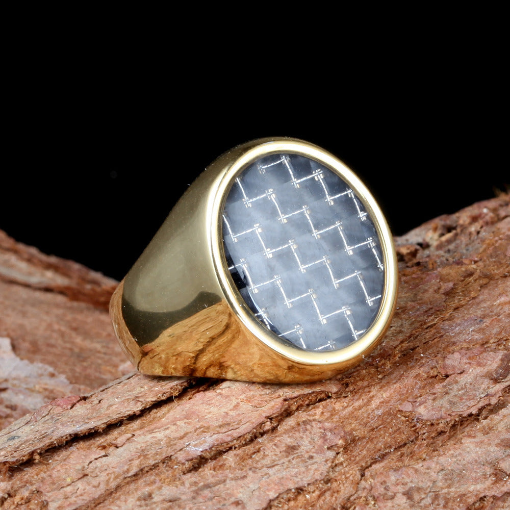 Gold ring with a geometric patterned stone on a wooden surface