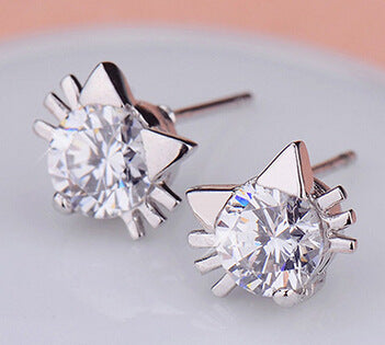 Pair of silver cat-shaped earrings with clear gemstones on a light gray background